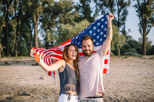 Young happy couple on beach with us flag
