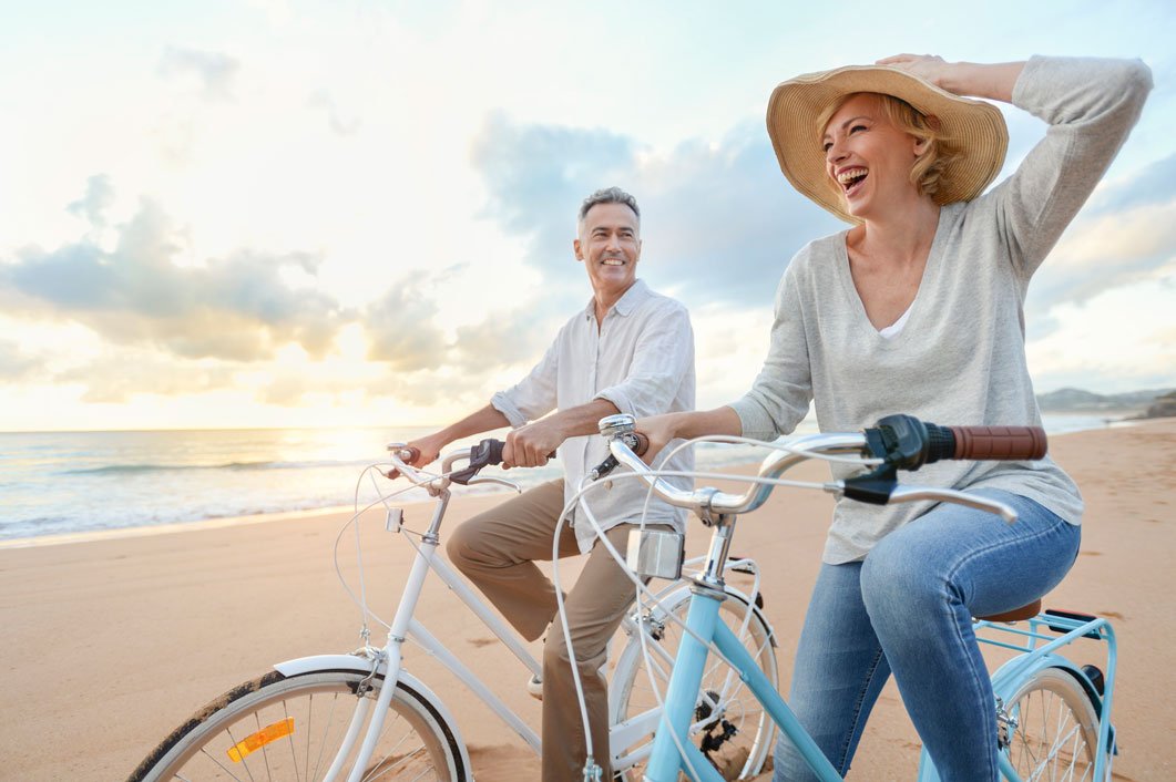 Mature couple cycling on the beach