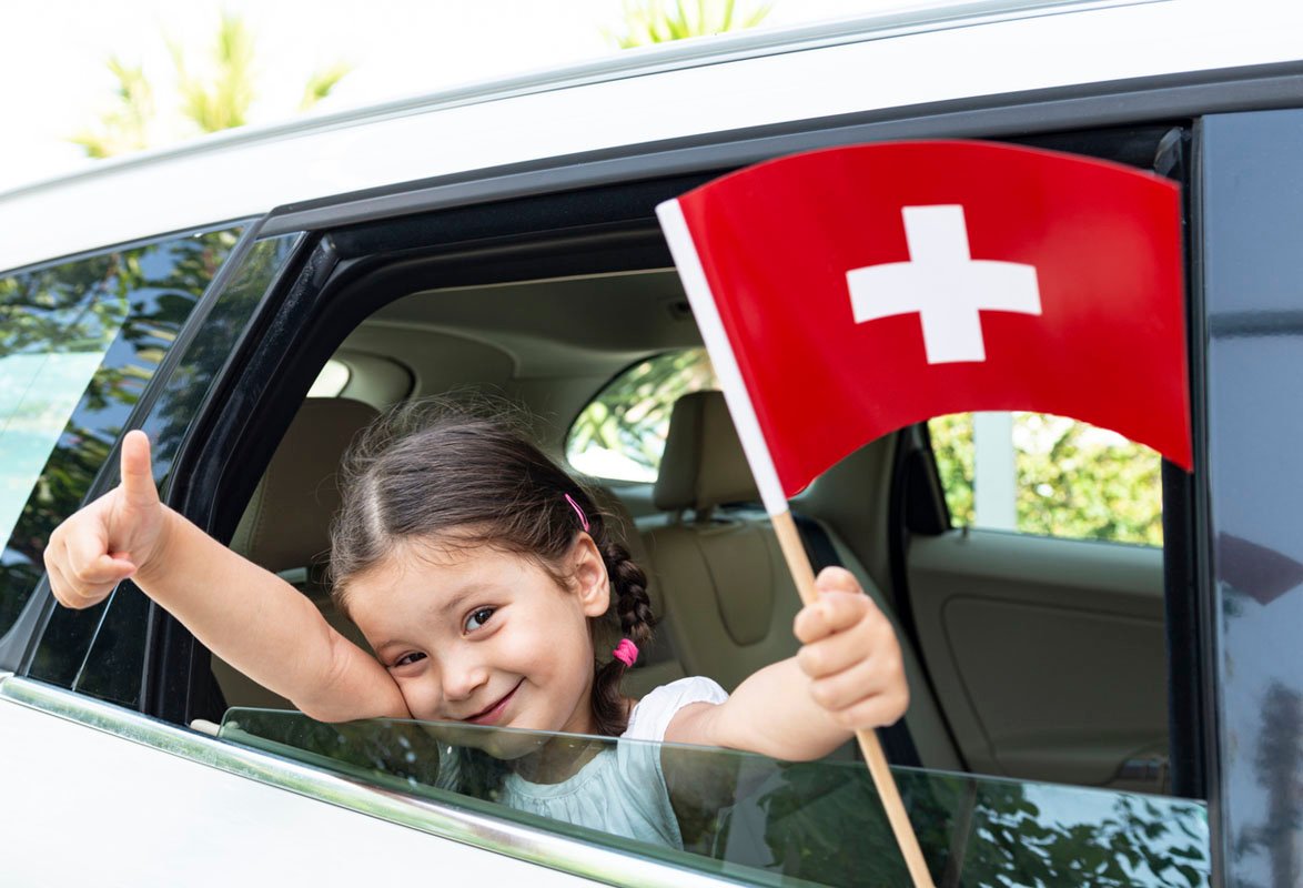 Petite fille en voiture tenant le drapeau suisse