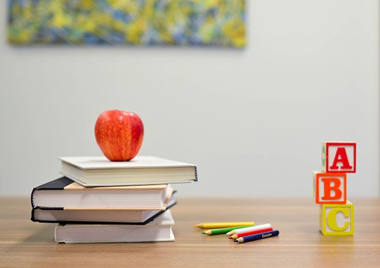 Books, apple, pencils and alphabet  blocks on desk