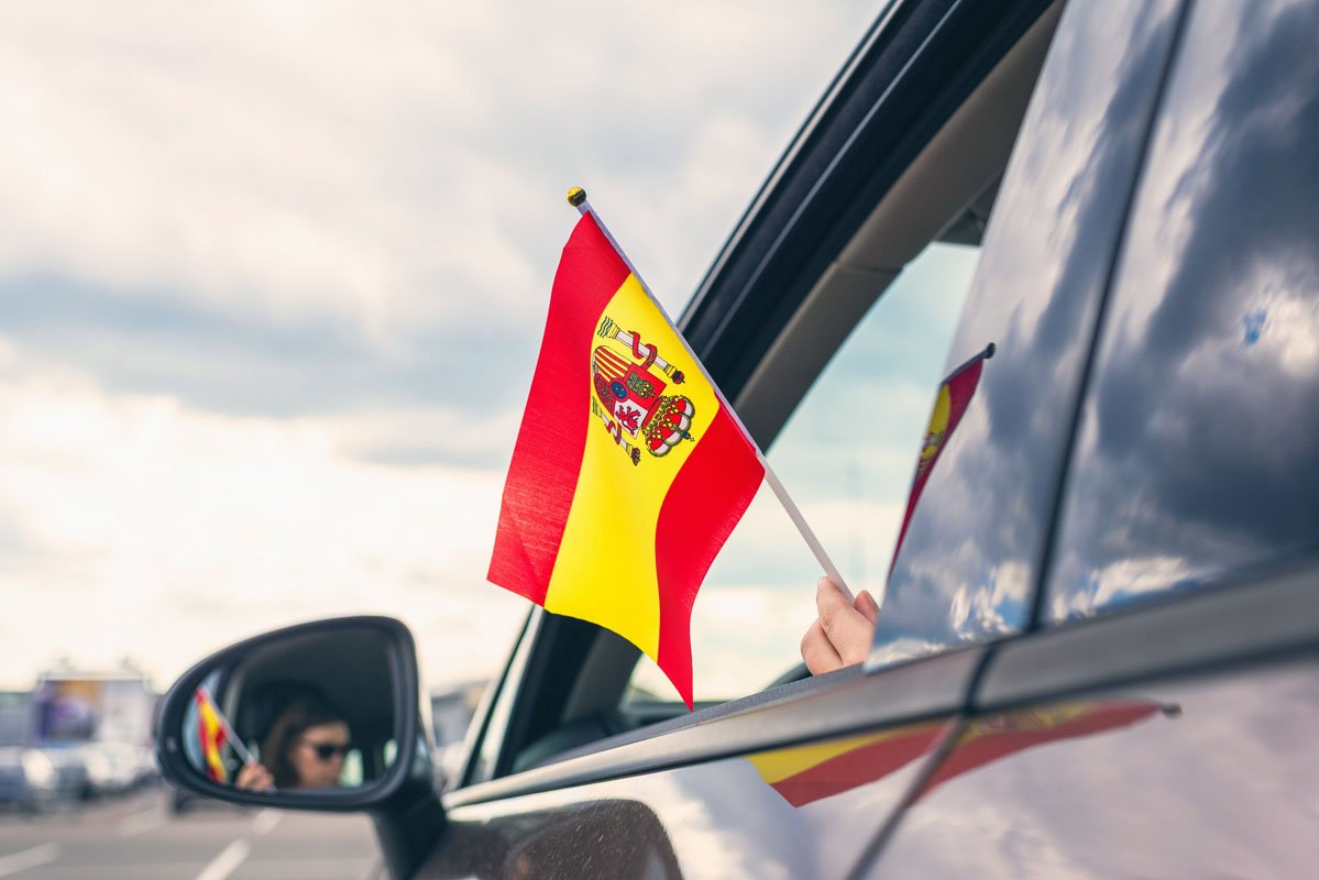 Bandera española ondeando por la ventanilla del coche