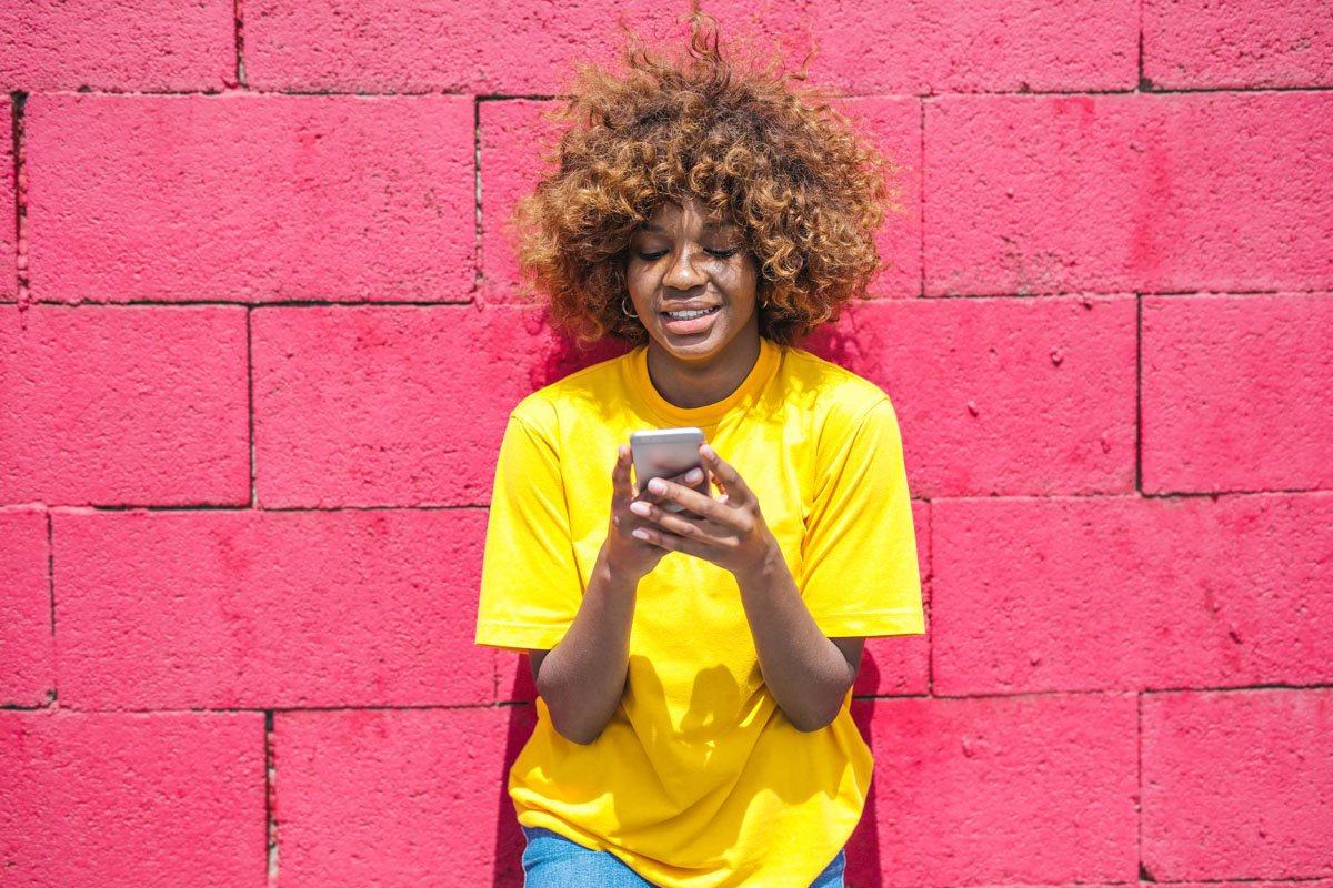 young black assignee on smartphone against pink wall