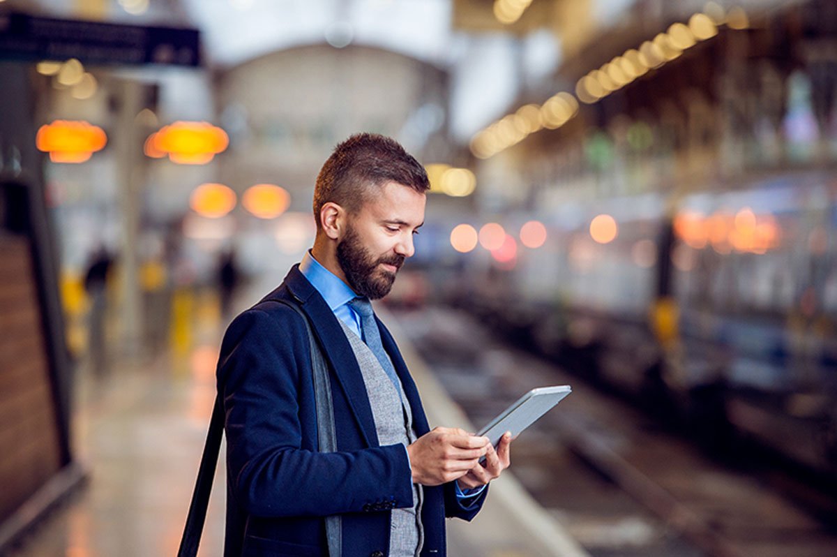 Business man looking at tablet at train stop