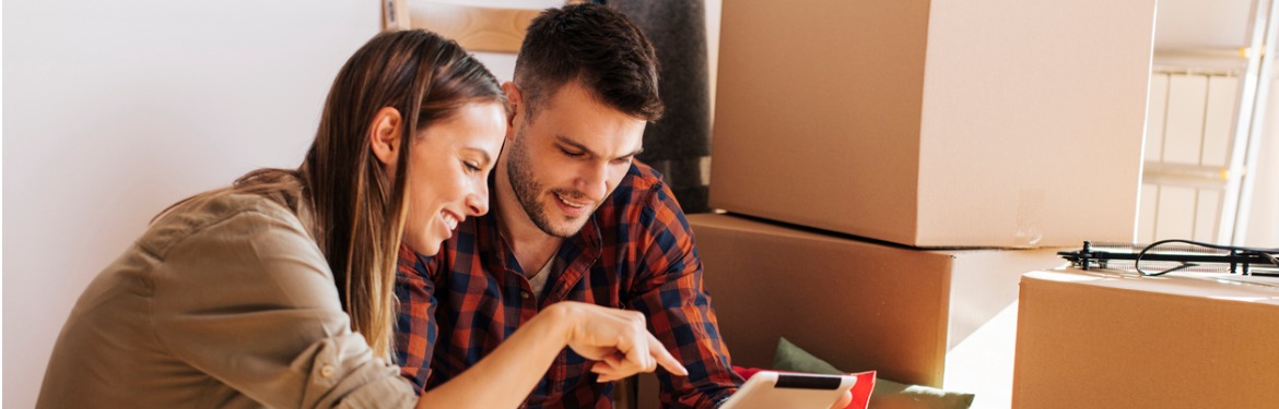 young couple looking at tablet in new apartment